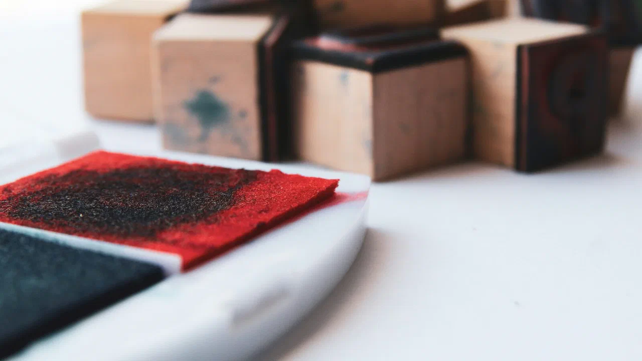 An ink pad lying open beside a group of wooden rubber stamps