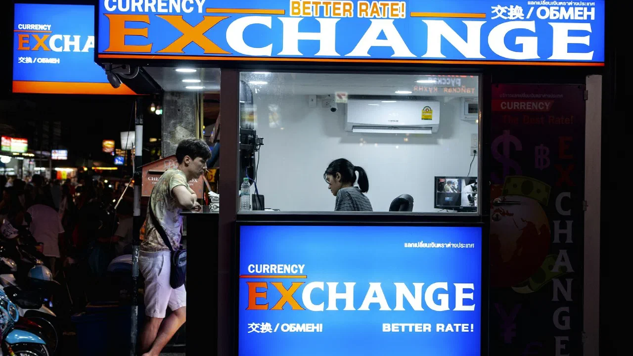 A person standing at the window of a currency exchange booth