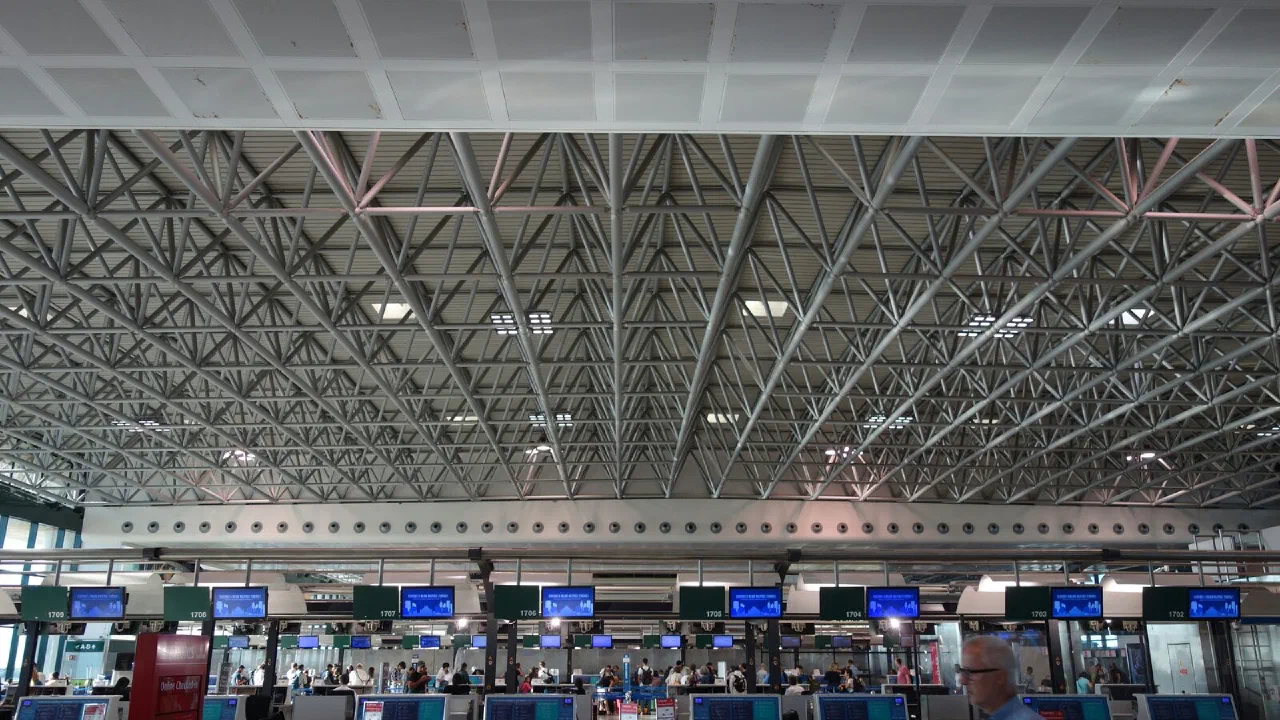 A row of empty airport check-in counters with lit electronic displays above them