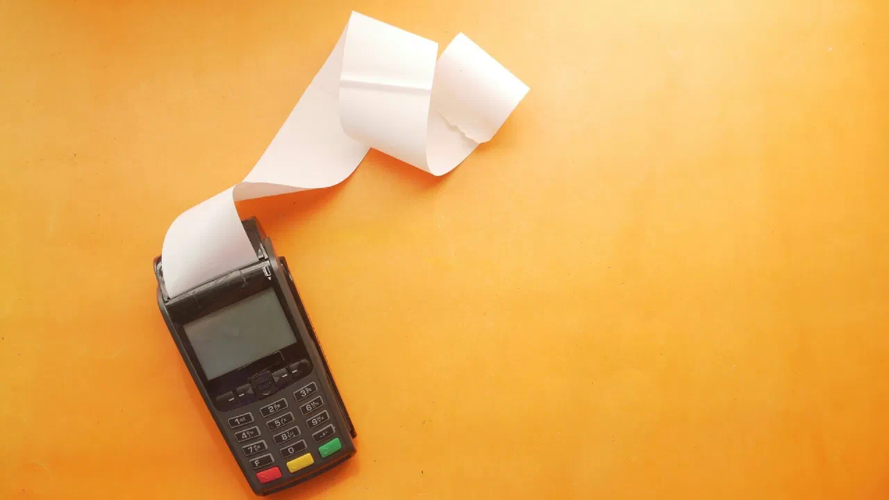 A card payment terminal with a long paper receipt curling away from it